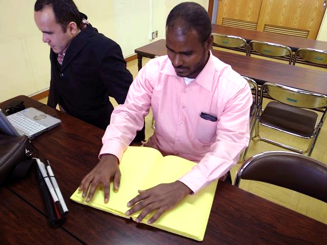 To defend the right to education for visually impaired children in Sudan, Abdin works through an NPO that provides braille textbooks. The man reading a braille textbook in the photo is CAPEDS Board Member Murtada Eljailani.