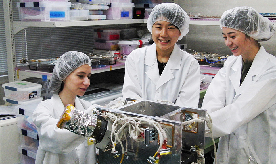 At Tohoku University’s Graduate School, Konaka (center) immersed herself in research on lunar exploration rovers and small satellites under Professor YOSHIDA Kazuya, who is involved in a number of international space projects. SPACE ROBOTICS LABORATORY, DEPARTMENT OF AEROSPACE ENGINEERING, TOHOKU UNIVERSITY
