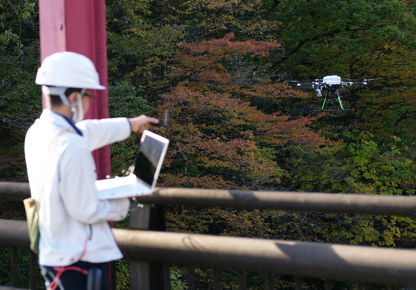 The picture depicts a bridge-survey experiment with a drone.