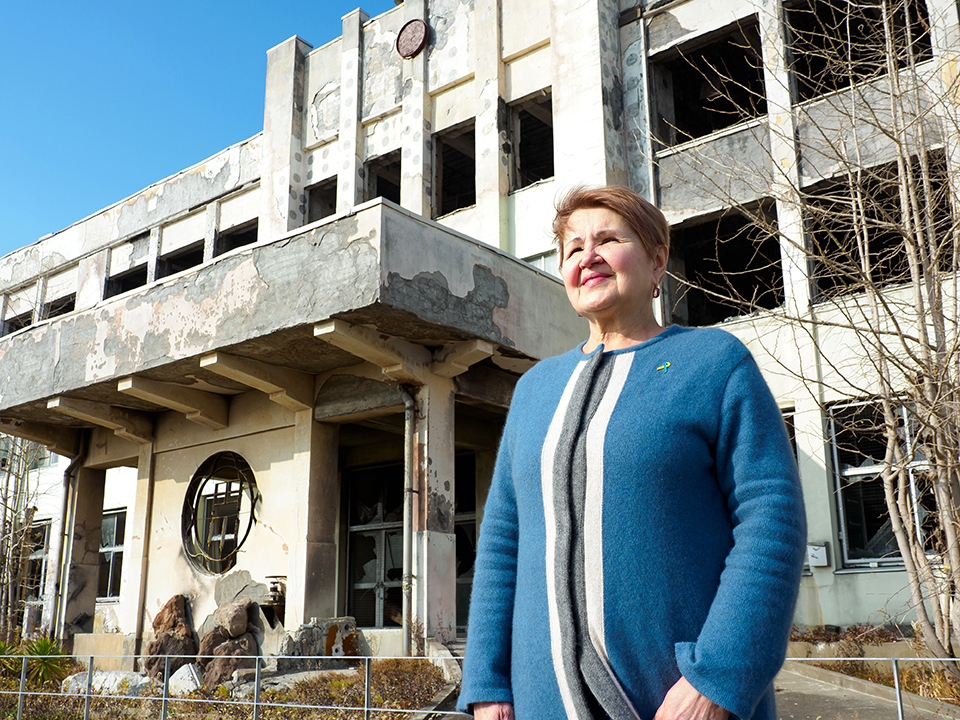 Irina Honcharova, a Ukrainian evacuee, stands in front of an elementary school building ruined by the tsunami.