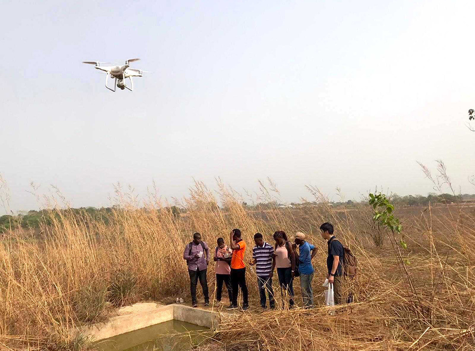 People watching a multicopter drone test flight in Sierra Leone.