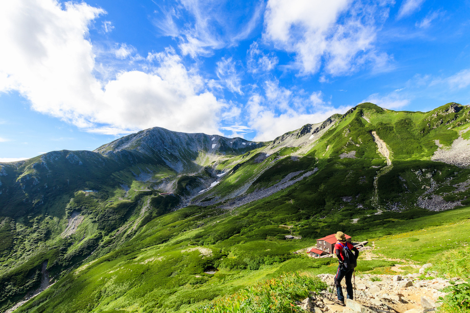 A hiker looking the beautiful green Mount Tateyama from the trail.