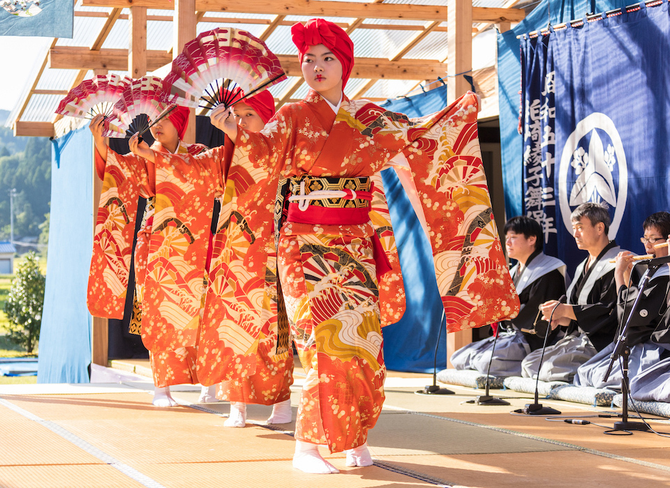 Dancers holding red and white fans, performing the Ayakomai dance in Kashiwazaki City, Niigata Prefecture.