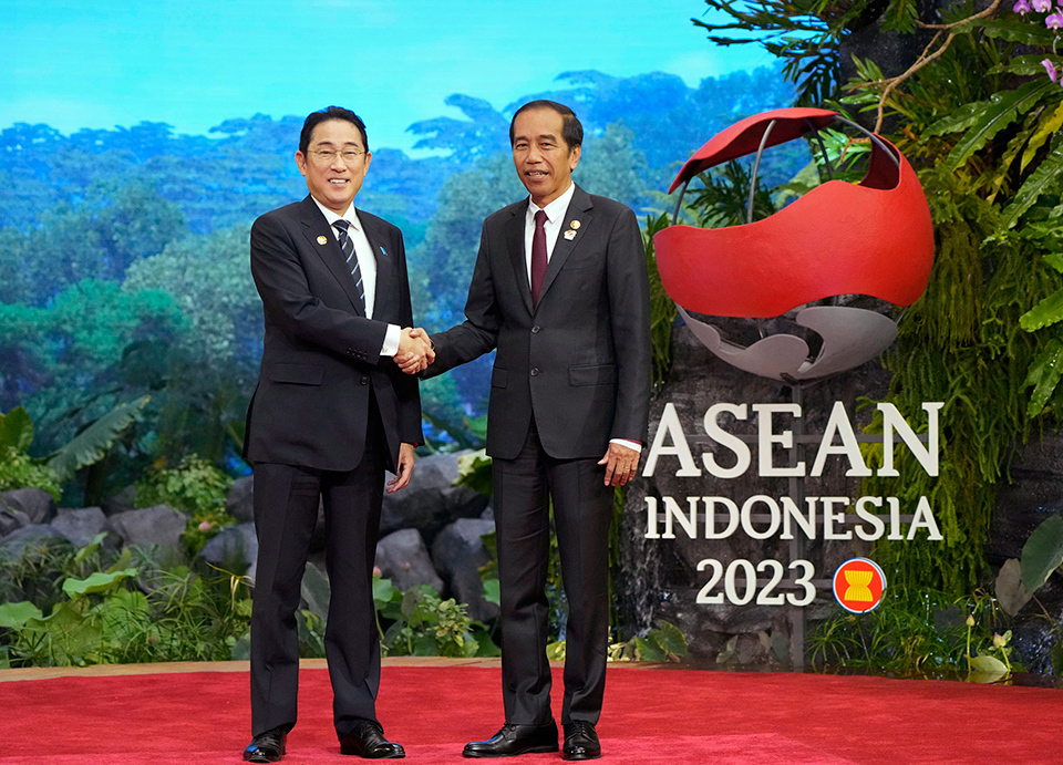 Japanese Prime Minister Kishida and Indonesian President Joko Widodo shake hands in front of the ASEAN Indonesia 2023 sign