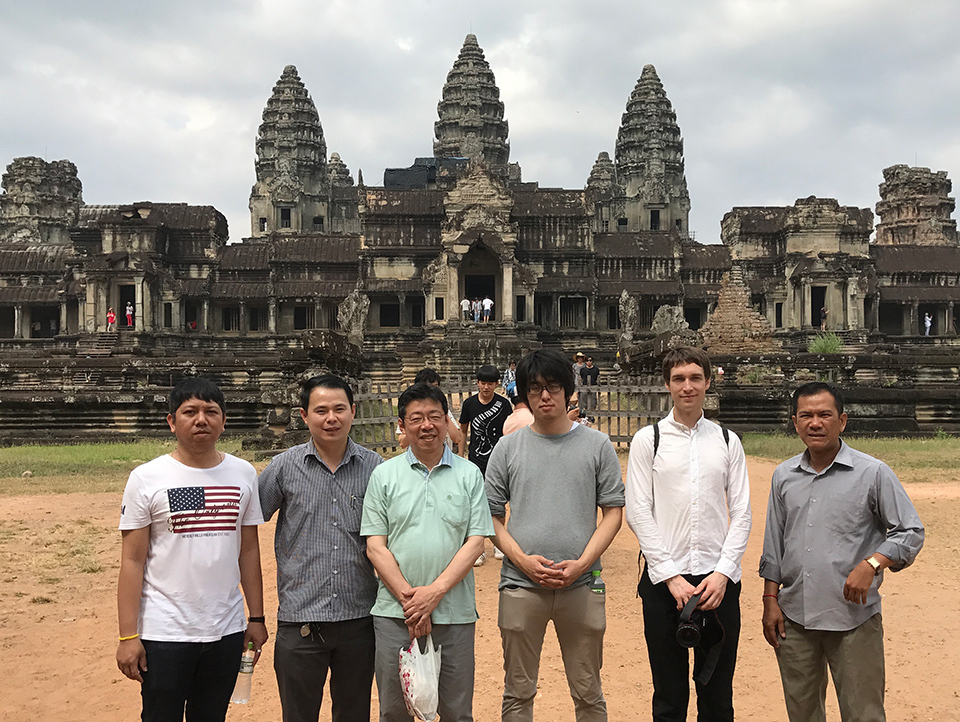 Six people standing in front of an ancient temple complex in the background.