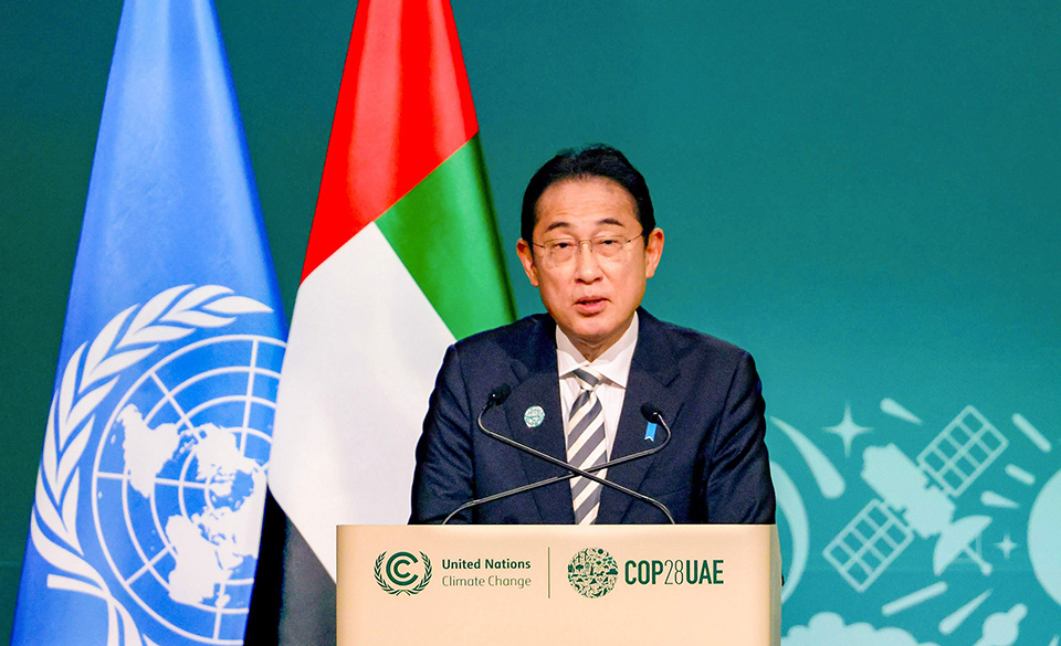 Prime Minister Kishida delivering a speech at the COP28 in Dubai, United Arab Emirates,  the flags of the United Nations and the UAE in the background.