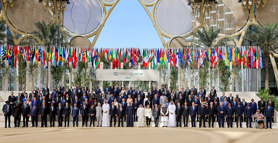 A large group of world leaders gathered for the World Climate Action Summit at COP28 in Dubai, United Arab Emirates, in front of a numerous flags.