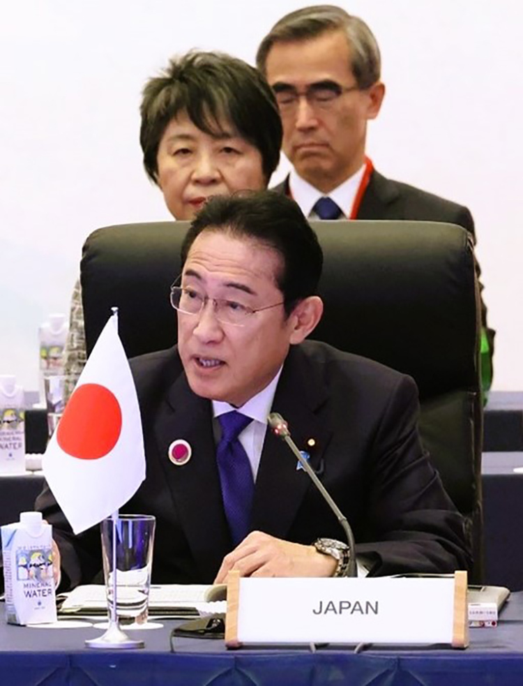 Prime Minister Kishida and other delegates seated at a conference table, with the Japanese flag prominently displayed in front of them.