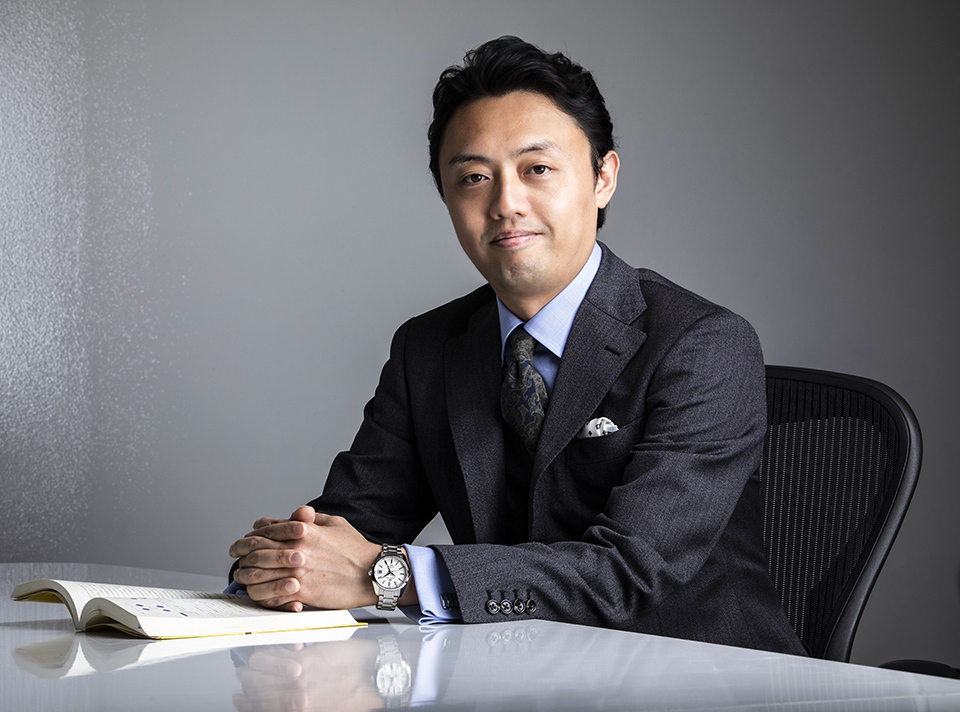 Professor MATSUO Yutaka of the University of Tokyo’s Graduate School of Engineering, dressed in a dark-colored suit, seated at a white table.