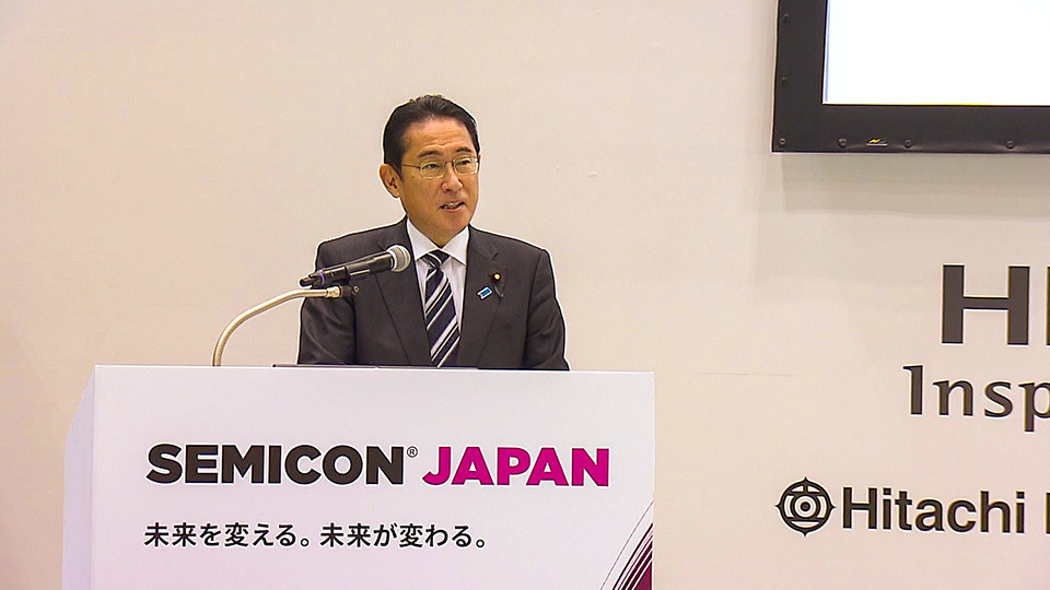 Prime Minister Kishida giving a speech at the SEMICON Japan eventv in 2022, standing behind a podium.
