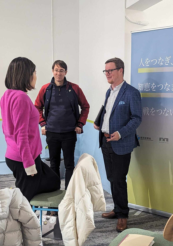 Three people are standing and discussing at Japan Innovation Campus.
