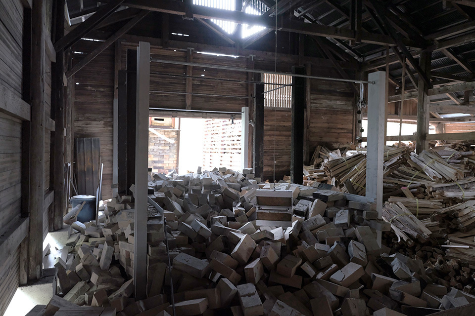 The old, wooden workshop filled with rubbles, with natural light seeping in through broken gaps in the walls.