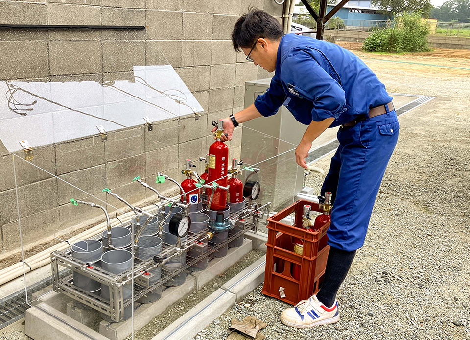 Delivery driver in blue is connecting the cylinder to an outdoor residential hydrogen fuel cell.