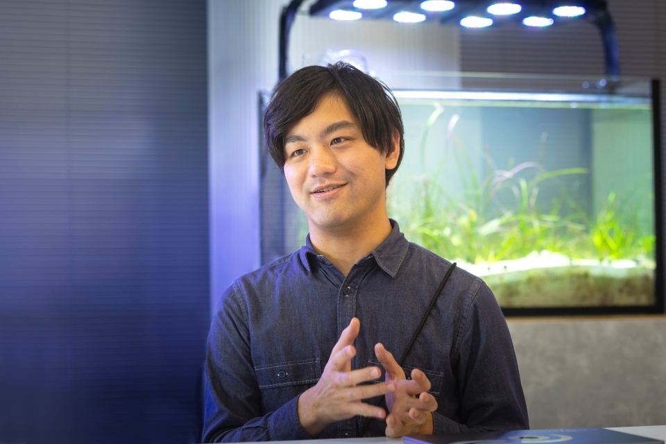 Innoqua Inc.'s COO, TAKEUCHI Shiki, with an aquarium in the background.