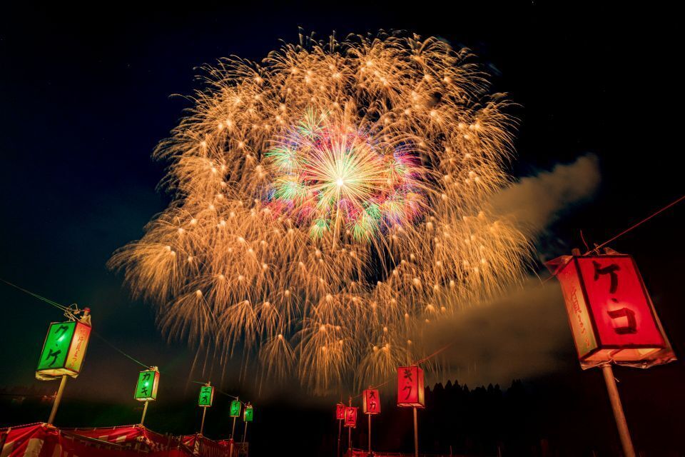 Colorful fireworks against a night sky, with red and green paper lanterns below