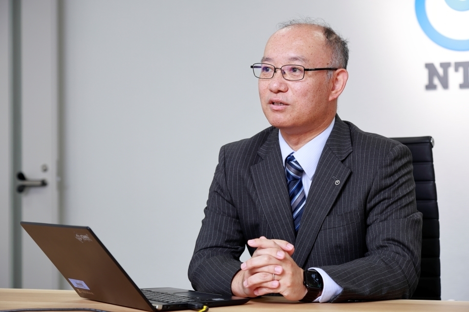A photo of Aragane Yosuke, in a dark suit against a white background with the NTT logo