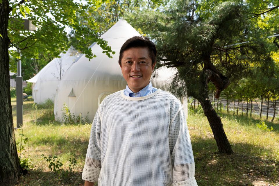 Kitagawa Keisuke standing in front of two white Instant Houses.