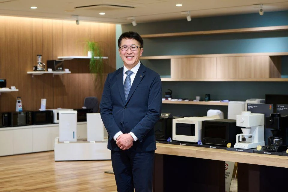 Nomizu Shigeaki, the President and CEO of Twinbird Corporation, standing in front of his company's appliances