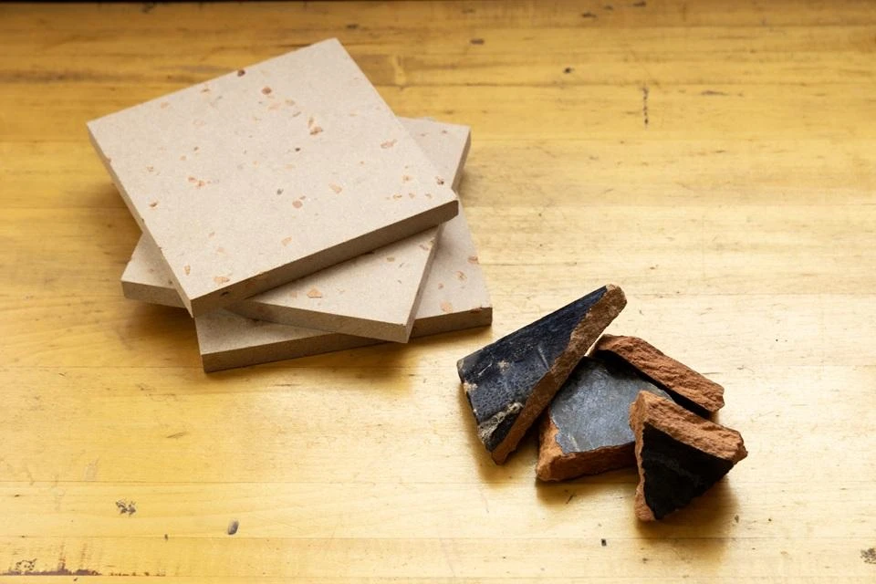 An image of broken black roof tiles and the new materials made from reusing them 