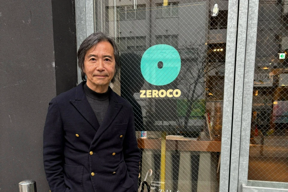 Kusumoto Shujiro, President and CEO of ZEROCO, posing in front of the company's logo. 