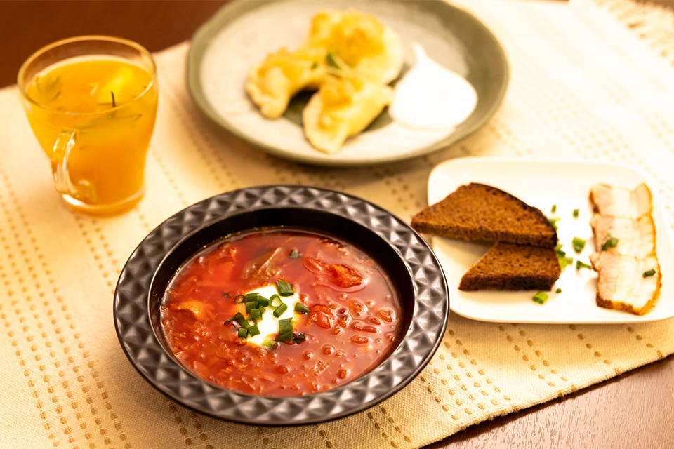 A table set with Ukranian cuisine, with a bowl of borscht soup in the foreground