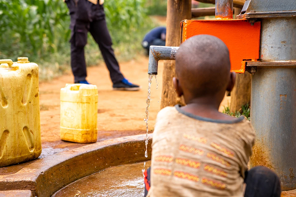 A child in Uganda getting water at a communal water source