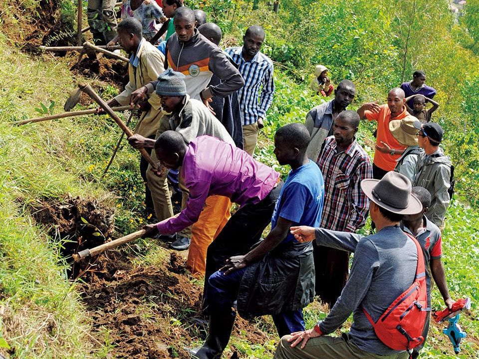 Rwandan coffee producers listen to Kawashima as he explains how to make terraced fields.