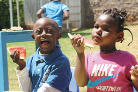 The children smile with delight in a watermelon eating contest.