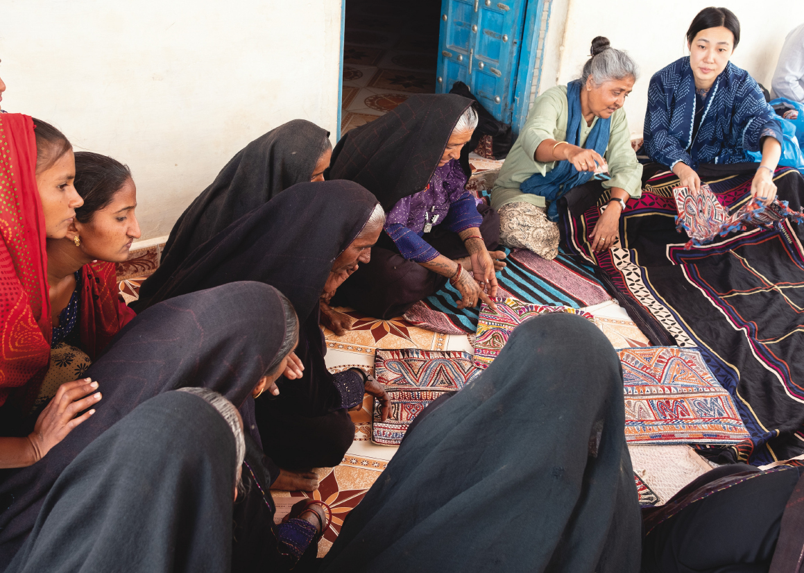Kobayashi sits together with members of Qasab (Qasab-Kutch Craftswomen’ Producer Co. Ltd.), which received the Nari Shakti Puraskar 2018 (Women Power Award), an award that the president of India gives to women who have contributed to society. She views a new embroidered product made by Rabari women and talks about the reaction by Japanese consumers to the products.